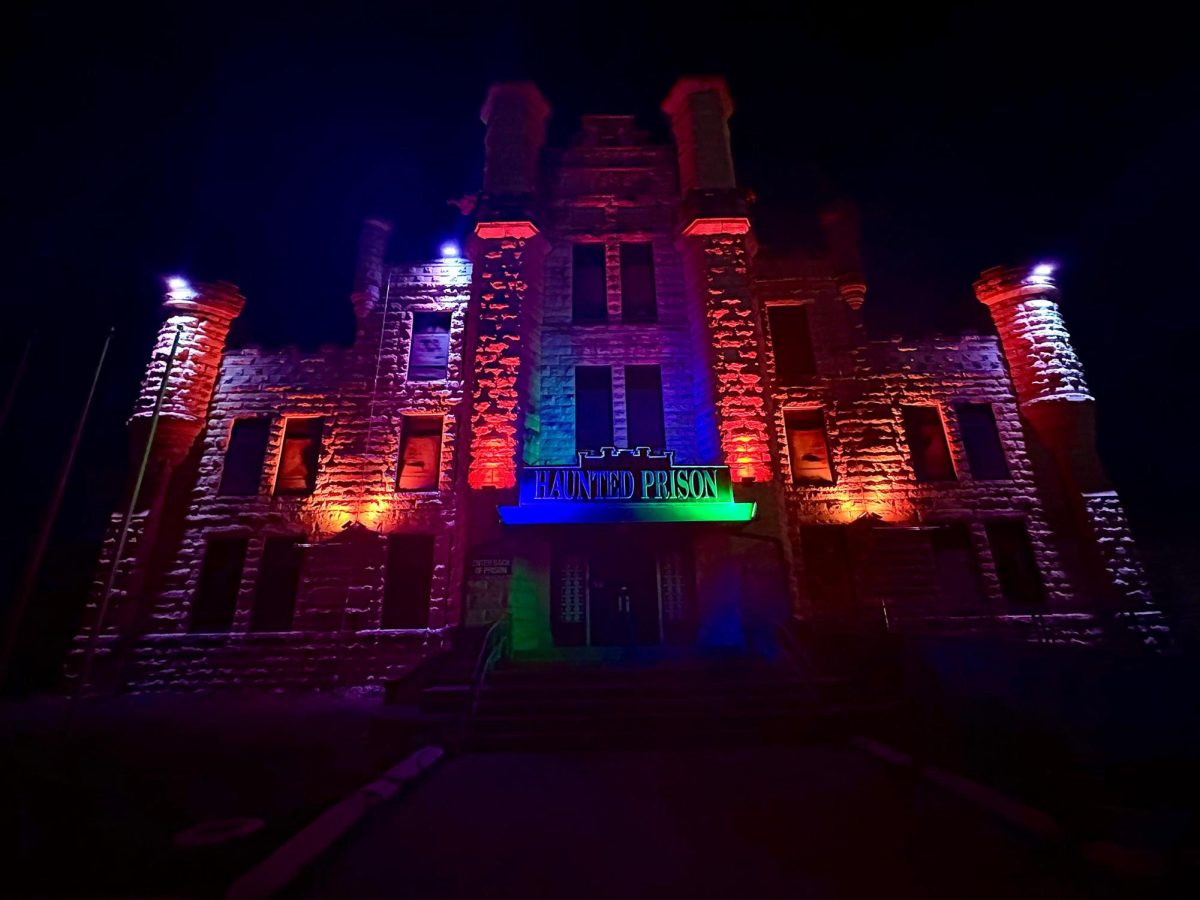 Above is the main entrance of the Joliet Haunted prison looming over as customers walk in. Lights illuminated all over the prison giving it an eerie glow.