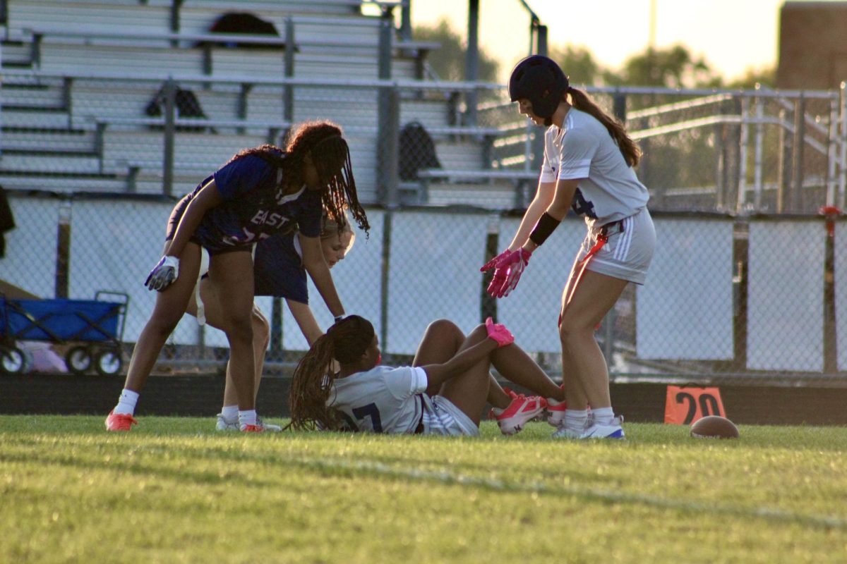 Players helping their teammate get up after falling. Showing sportsmanship for their fellow player.